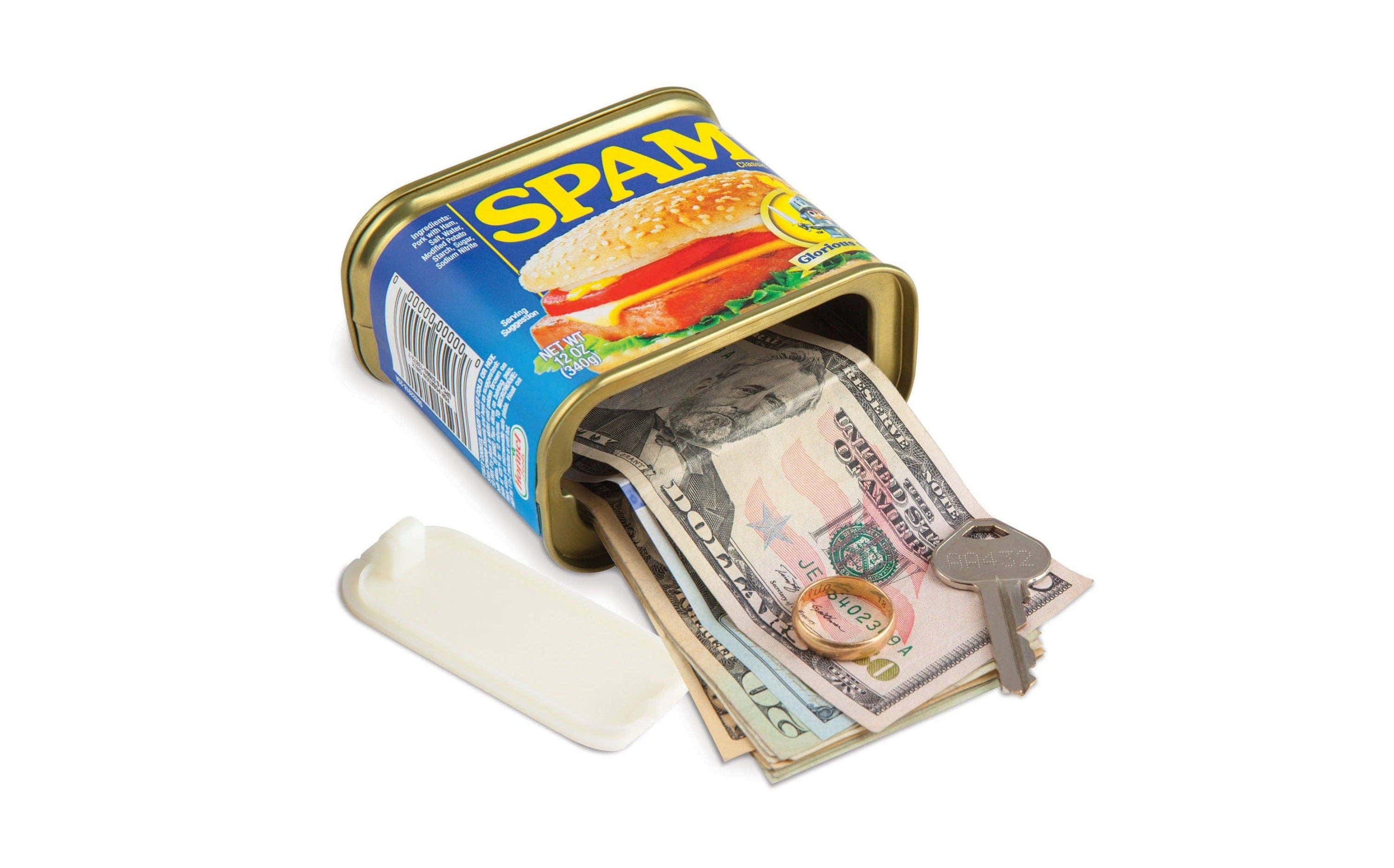 A Spam can with its lid open, revealing stacked US currency and a key inside. The setup suggests clever concealment, adding a humorous, unexpected twist.