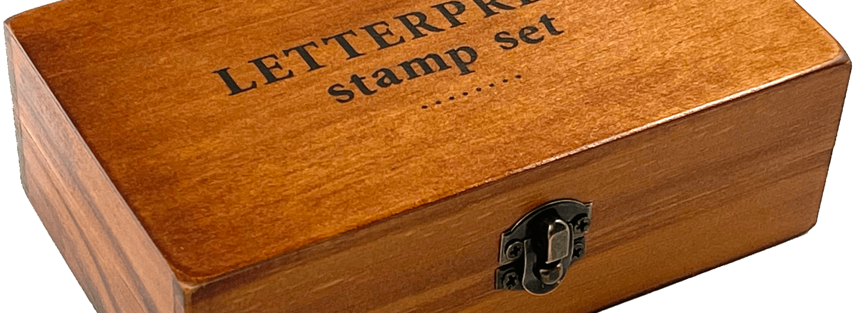 A wooden box labeled "LETTERPRESS stamp set" with a metal latch, resting on a transparent background. The box has a warm, polished finish.