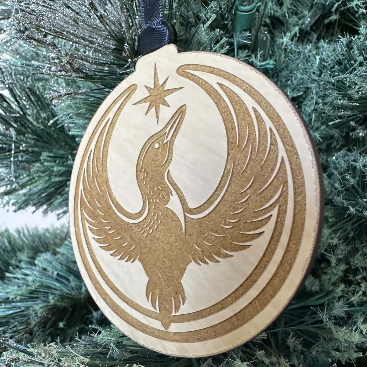 Rebel Loon wood ornament held by its black hanging ribbon