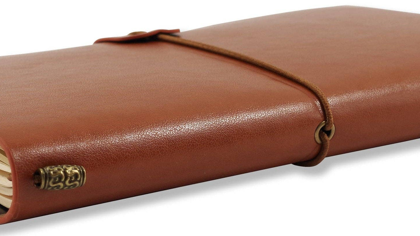 Brown leather notebook with a wraparound cord, closed, resting on a white surface. Pages slightly visible, conveying a vintage, elegant feel.