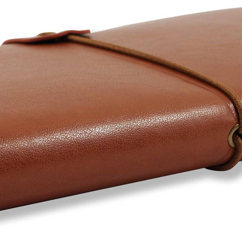 Brown leather notebook with a wraparound cord, closed, resting on a white surface. Pages slightly visible, conveying a vintage, elegant feel.