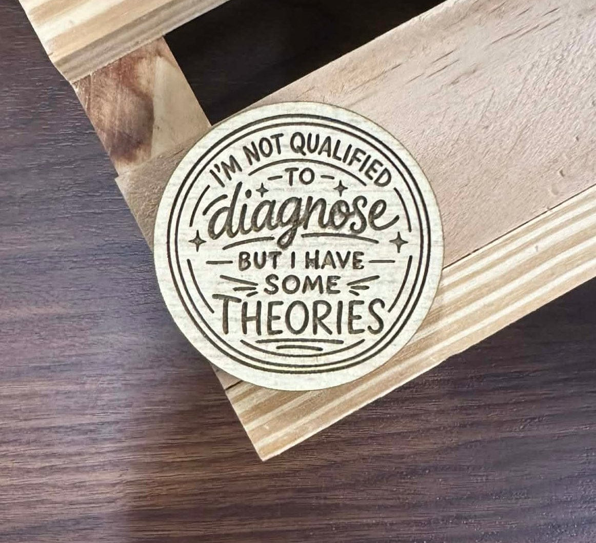 Circular sticker with text on a wooden surface.Text states "I'm not qualified to diagnose, but I have some theories."
