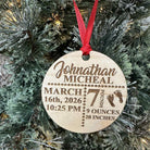 Wooden ornament with engraved baby details on a Christmas tree.