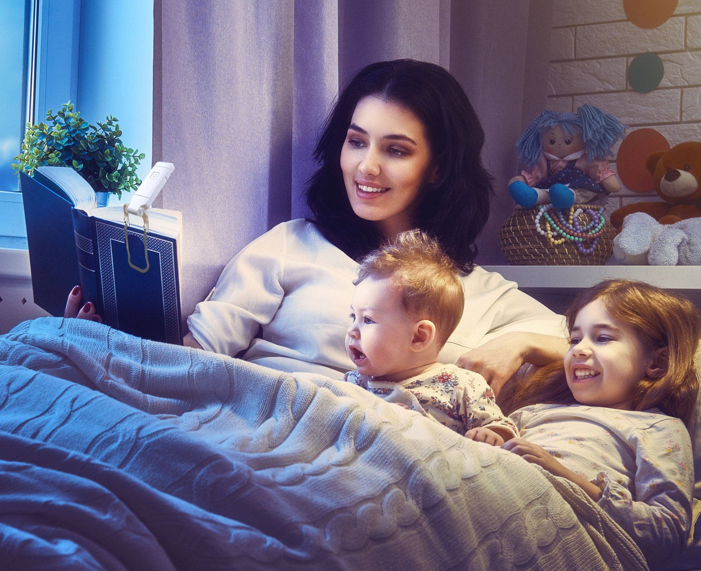 A mother reads to her smiling children in bed under soft lighting. Toys decorate a shelf behind them, creating a cozy and warm bedtime atmosphere.
