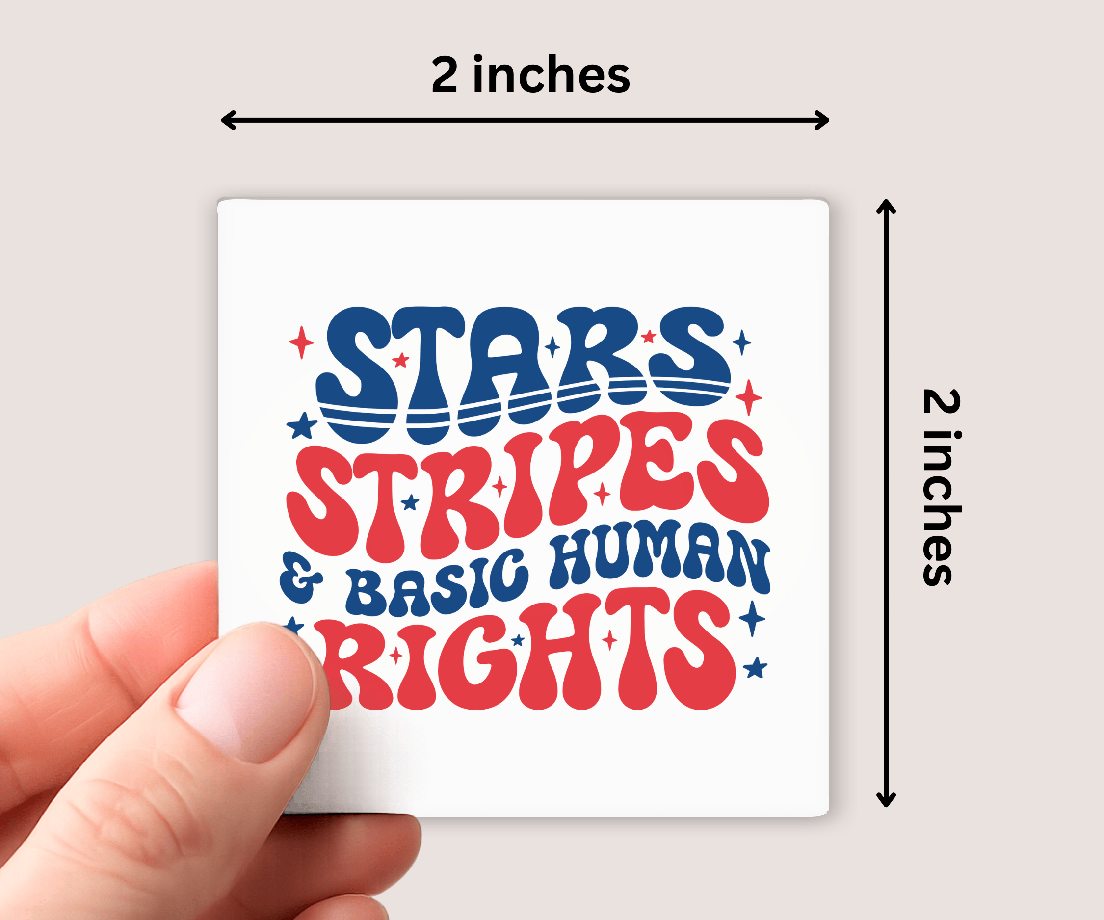 Hand holding a small square magnet with 'Stars Stripes & Basic Human Rights' text, measured at 2x2 inches.