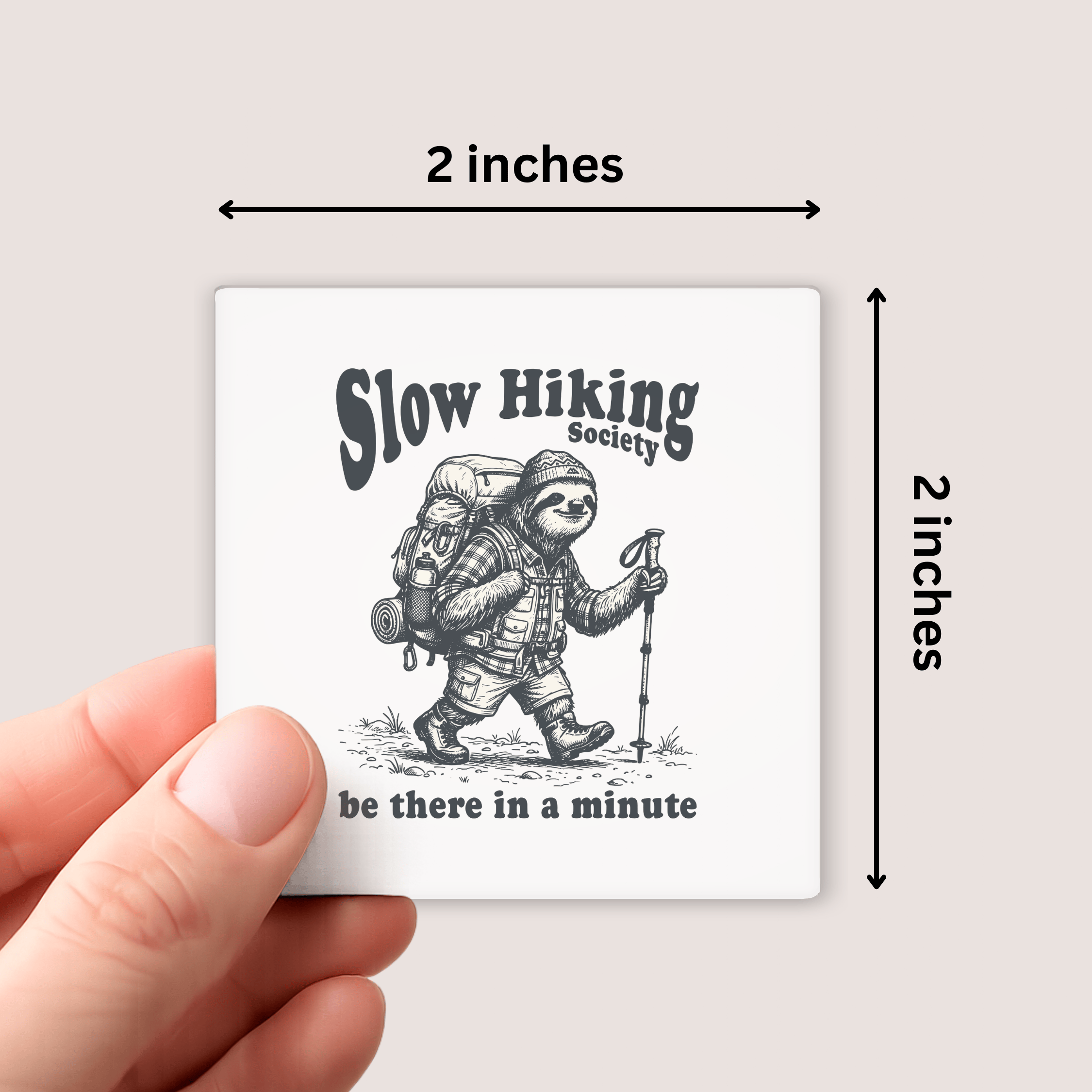 Small square magnet with a sloth illustration and text held by a hand, showing dimensions.