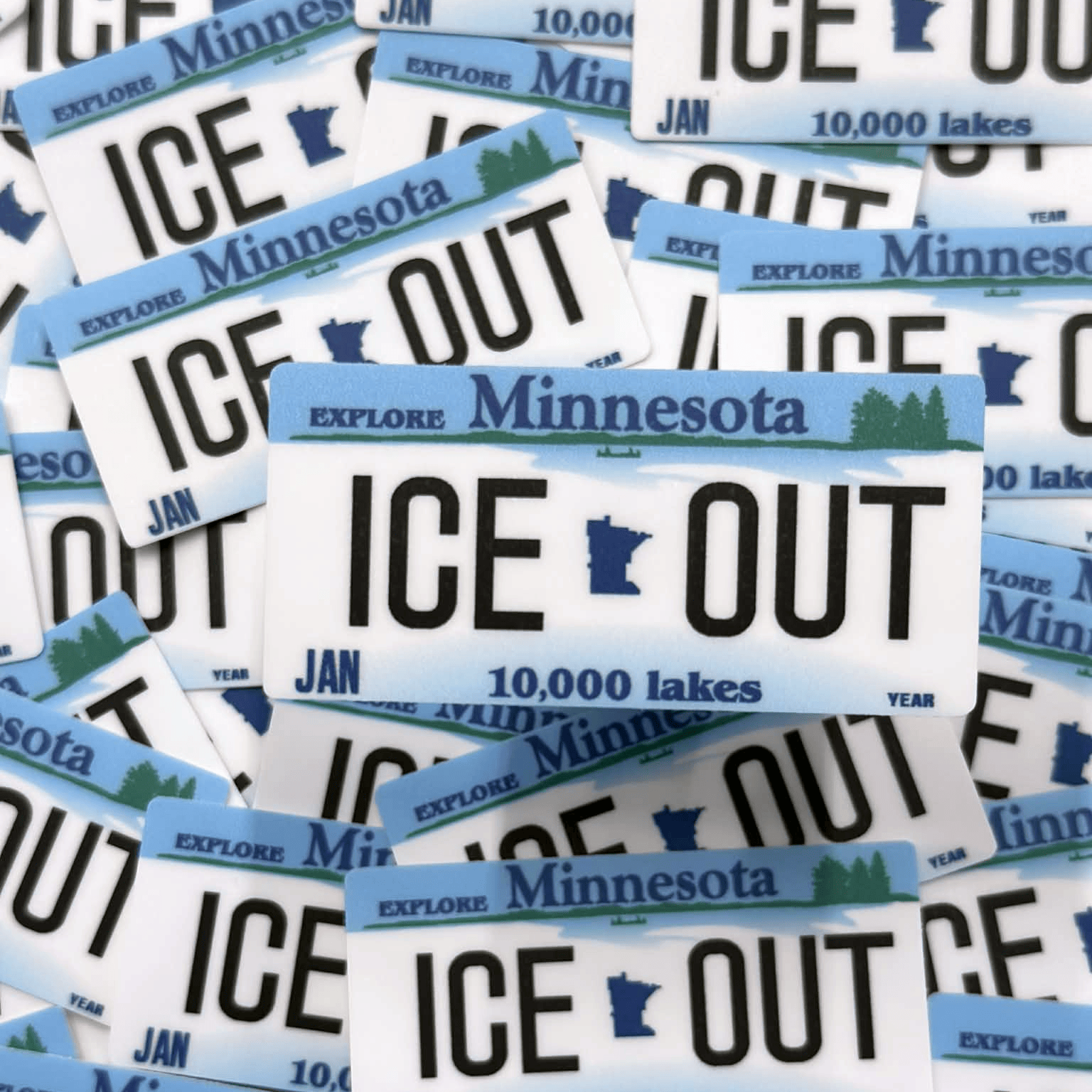 Stack of 'ICE OUT' Minnesota license plates with text about lakes.