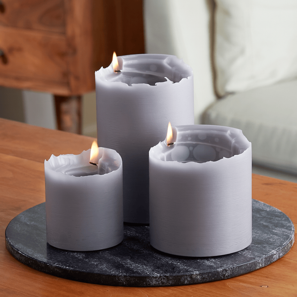 Three white candles with a flame on a dark marble tray on a wooden surface.
