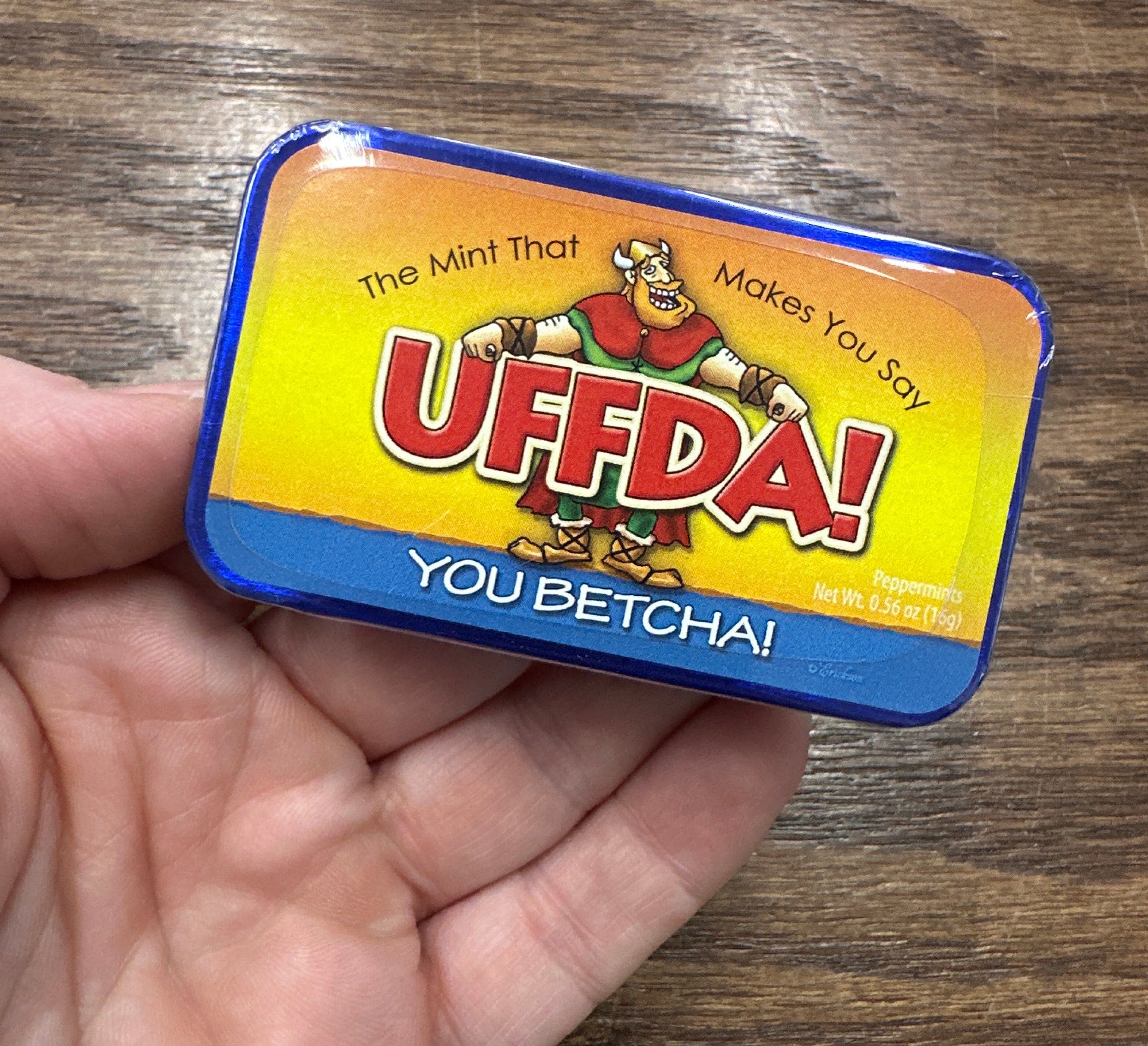 Mint tin with colorful label featuring cartoon character and text “U Betcha!” on a white background