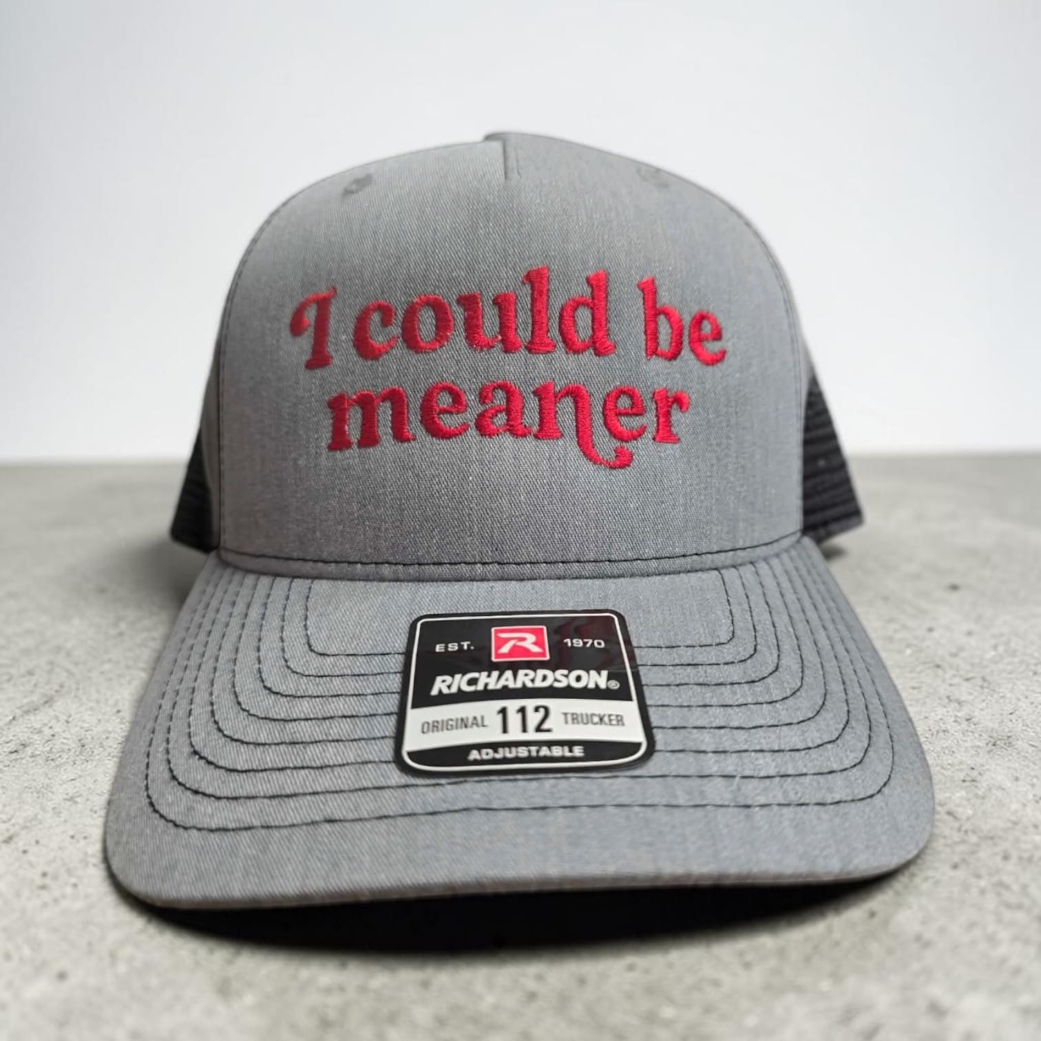 A gray Richardson 112 trucker hat with red embroidered text reading 'I could be meaner' on the front, shown against a neutral gray background.