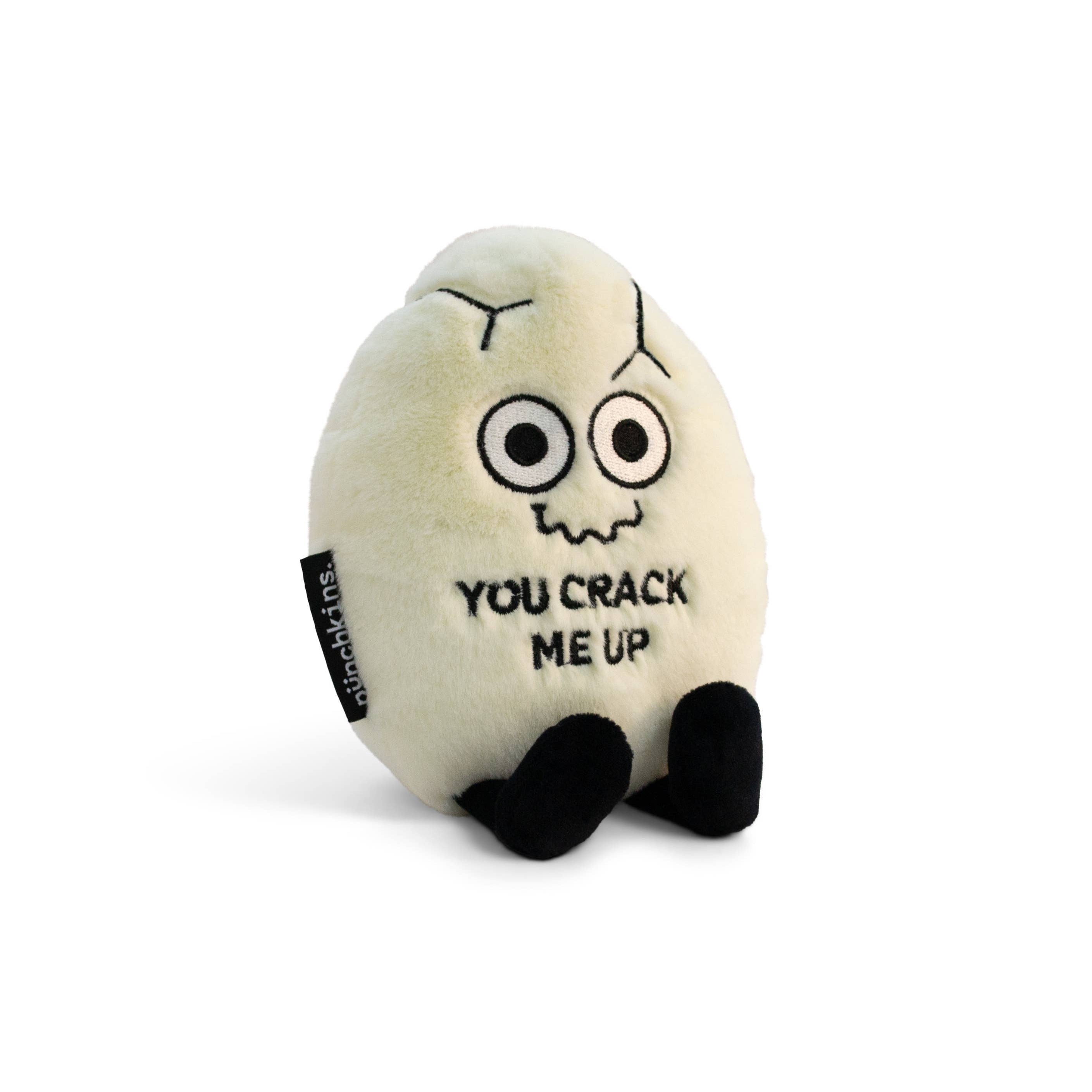 A white cracked egg plush with a squiggly smiley face and black text that says "You crack me up." The plushie has black legs sticking out.