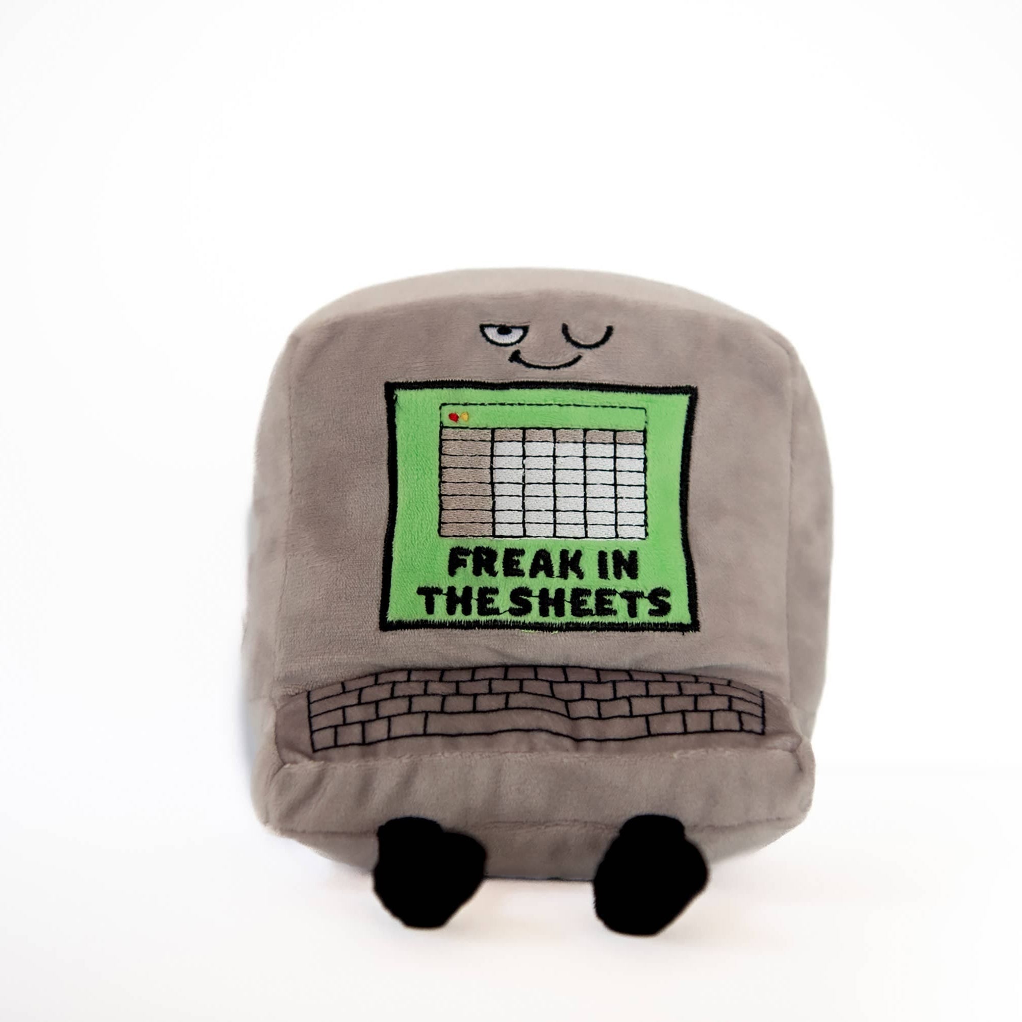 A gray computer plush with a winky face, featuring a green Excel-style sheet embroidered with the words "Freak in the Sheets" in black. It also has an outlined keyboard design and black legs sticking out from the bottom.