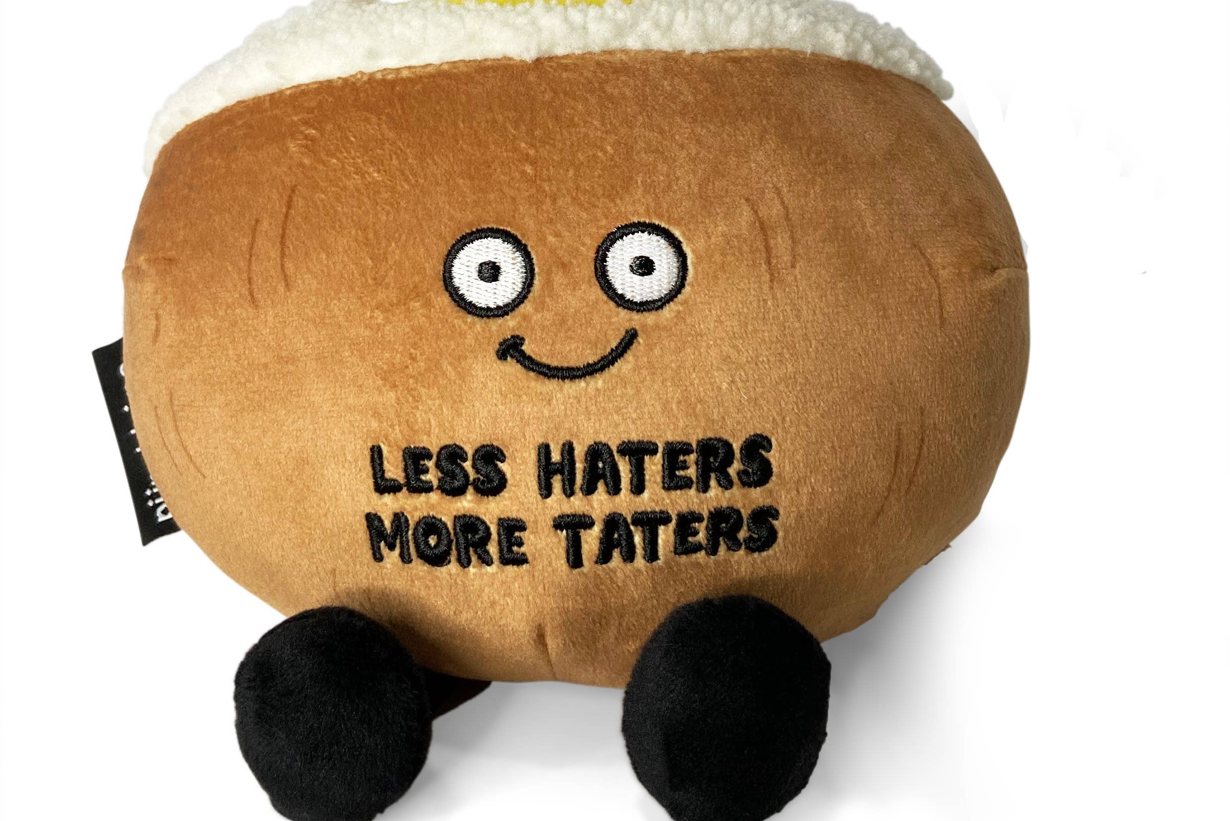 Brown baked potato plush with black legs, a white top, and a pat of yellow butter on top.