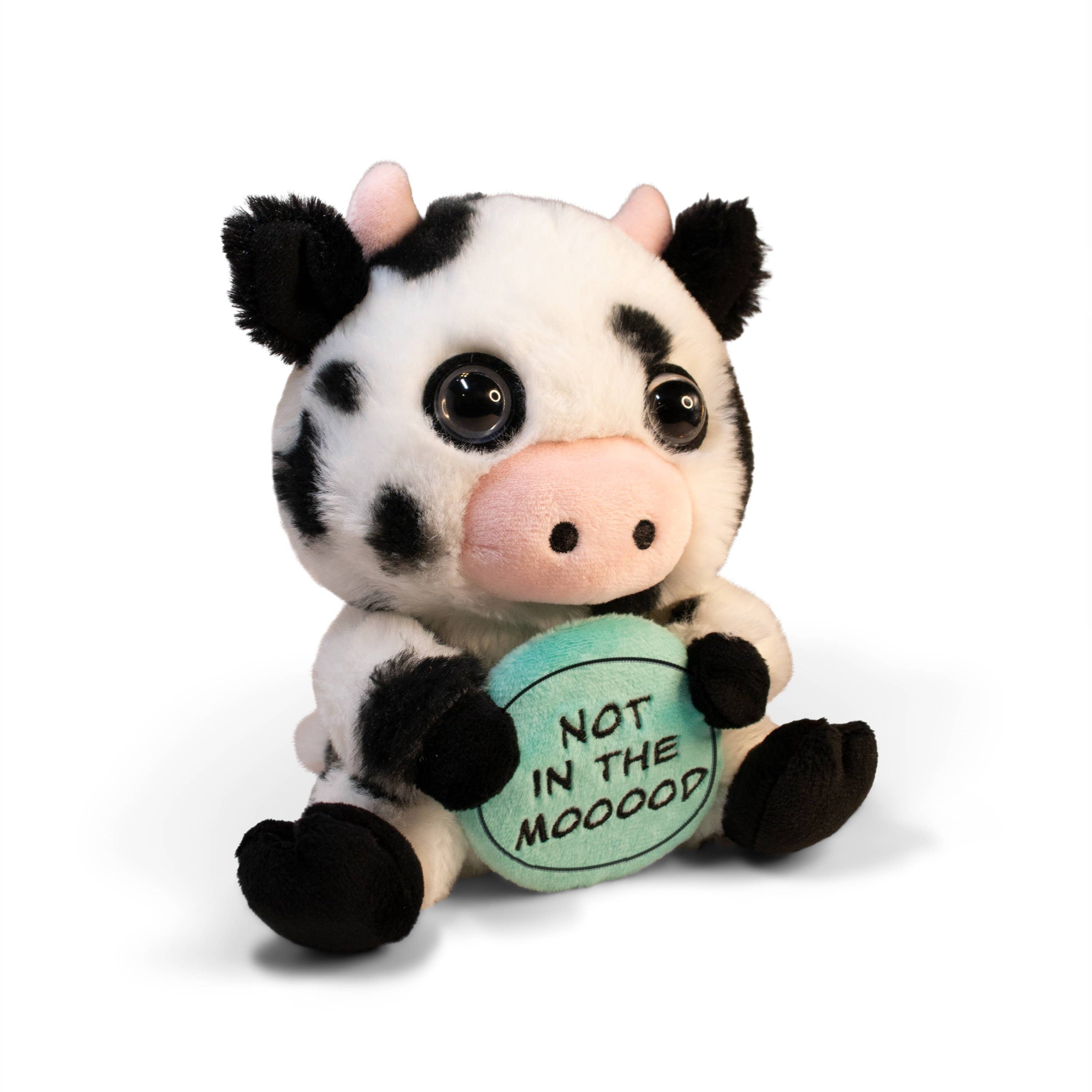 A black and white cow plush with pink horns, a pink nose, and glass eyes. The plush is holding a green plate with black text that reads 'Not in the Mooood,' giving it a playful and expressive look.
