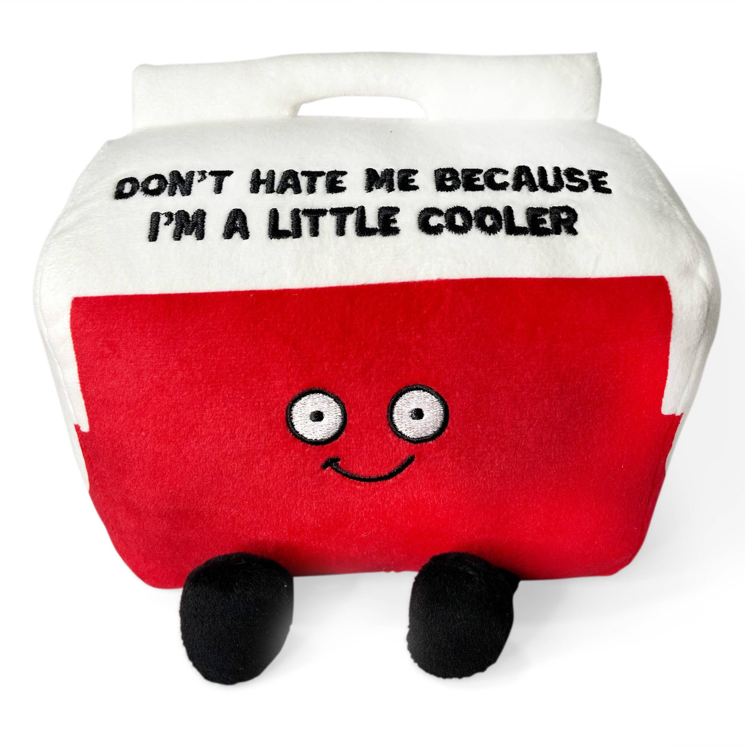 A cooler plushie with a white top and red bottom. The white top features black embroidered text that says, "Don't hate me because I'm a little cooler." The red section has a smiling face, with black legs sticking out from the bottom.