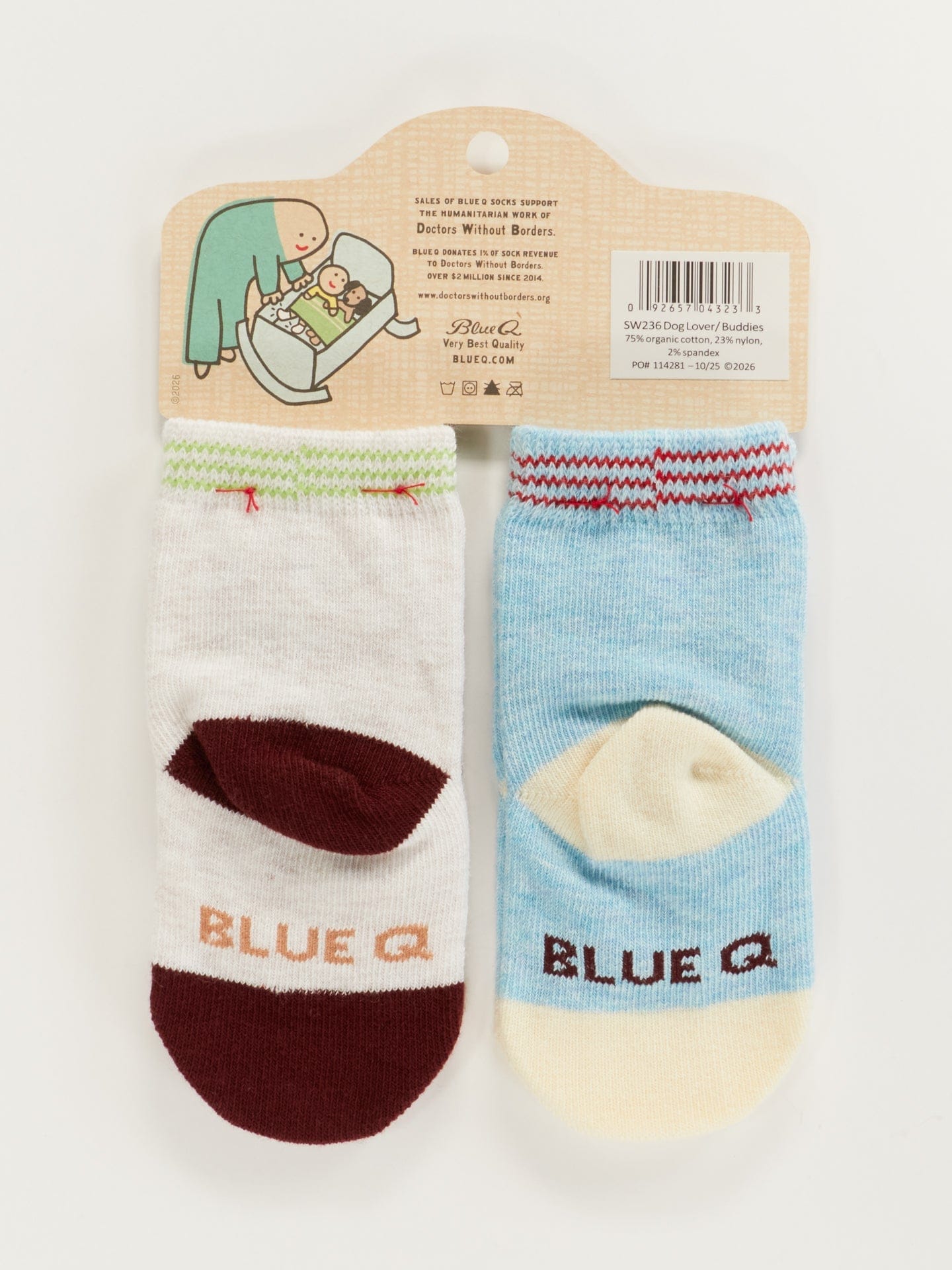Pair of light blue Blue Q baby socks with dark red heels and toes, featuring the 'Blue Q' logo on the soles. The packaging shows a whimsical illustration of a baby and puppy.