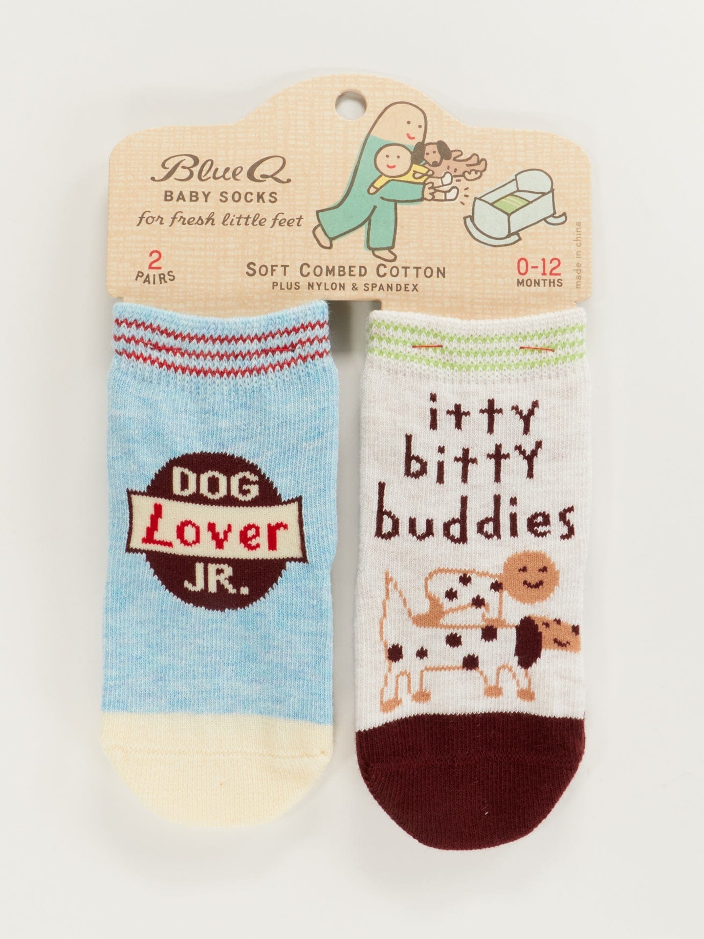 Two pairs of Blue Q baby socks; one pair is light blue with a 'Dog Lover JR.' patch, and the other is white with brown accents featuring a dog illustration and the text 'itty bitty buddies'.