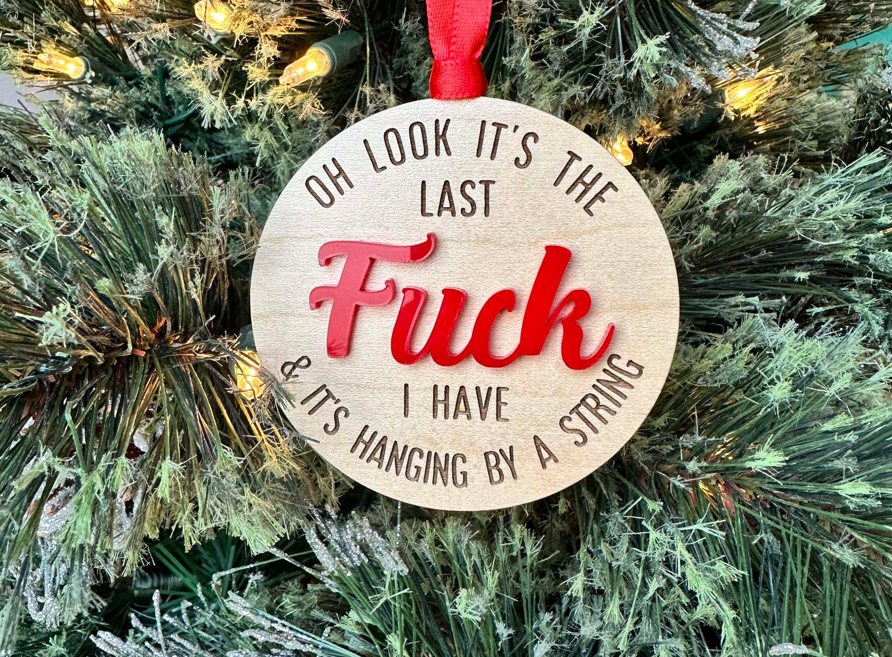 Wood ornament that reads " oh look it's the last fuck I have and it's hanging by a string" with the word "FUCK" in red.