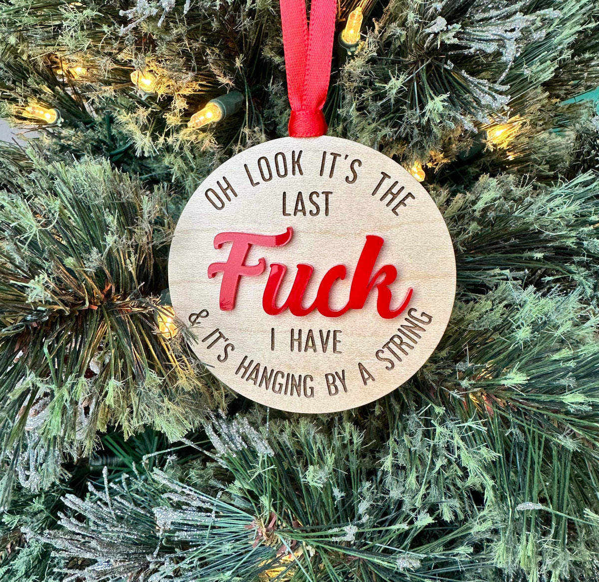Wood ornament that reads " oh look it's the last fuck I have and it's hanging by a string" with the word "FUCK" in red.