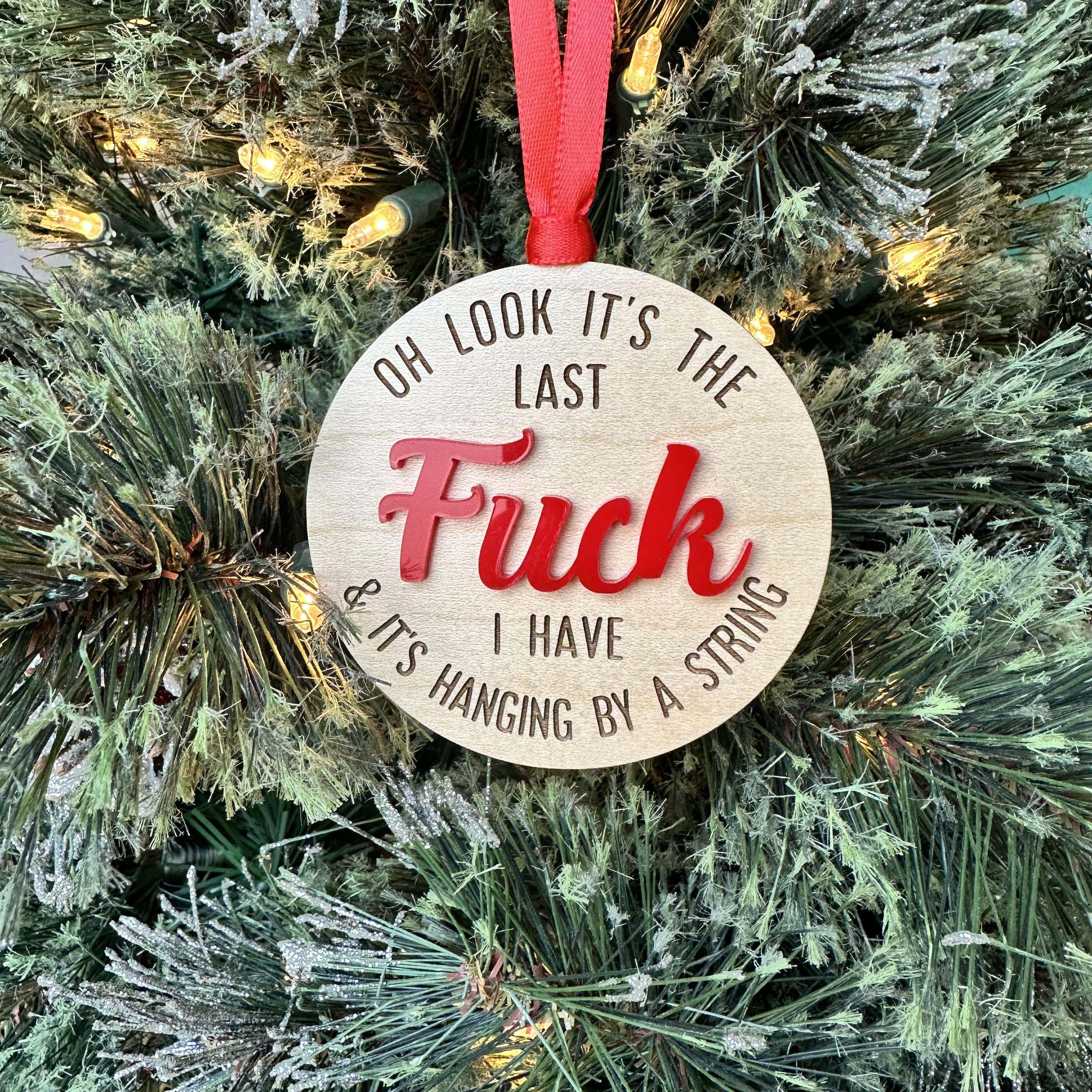 Wood ornament that reads " oh look it's the last fuck I have and it's hanging by a string" with the word "FUCK" in red.