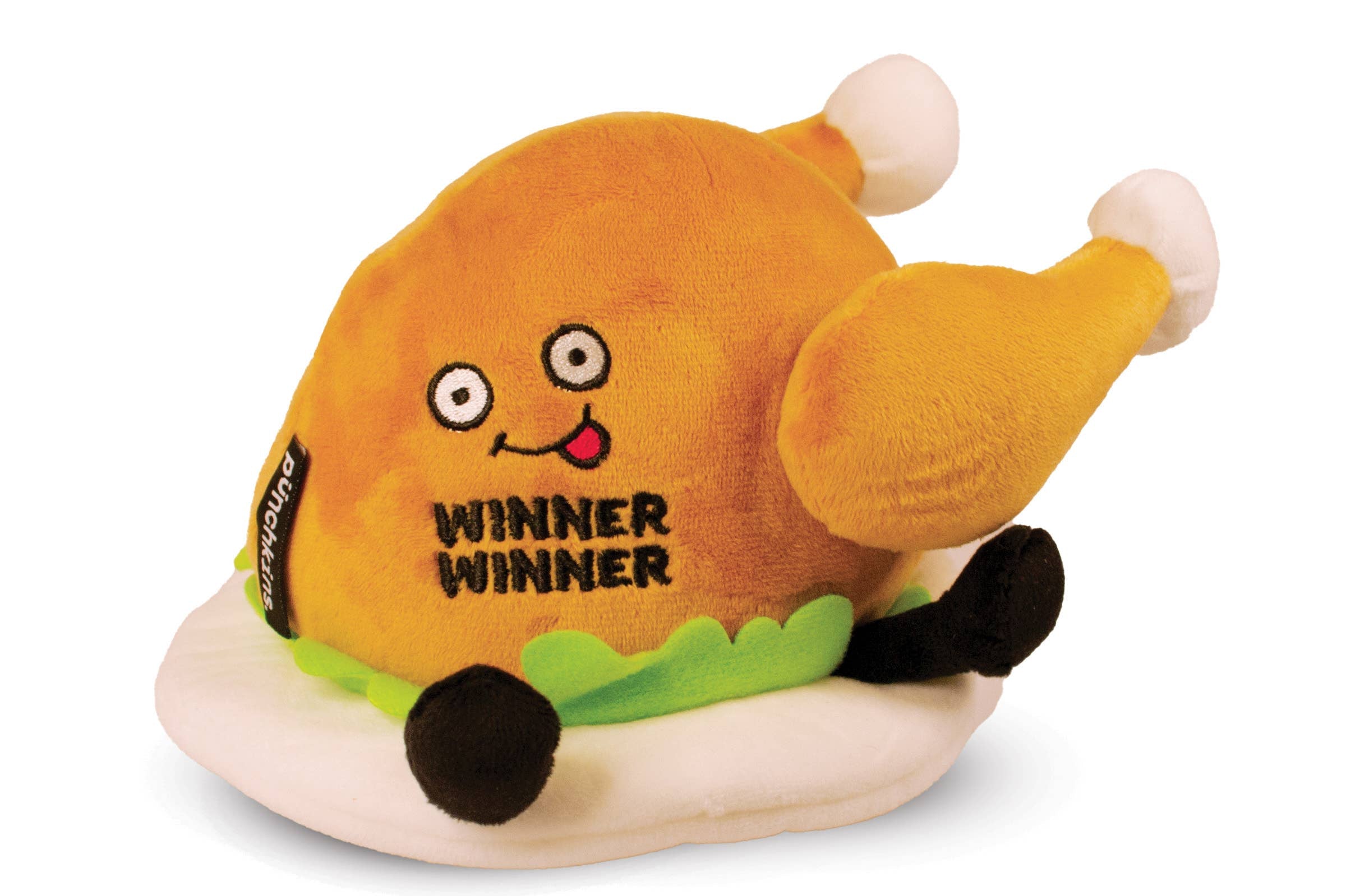 A cooked turkey dinner plush on a plate with green lettuce. The turkey has a smiley face with a red tongue sticking out and black text that says "Winner Winner." It also has black legs sticking out.