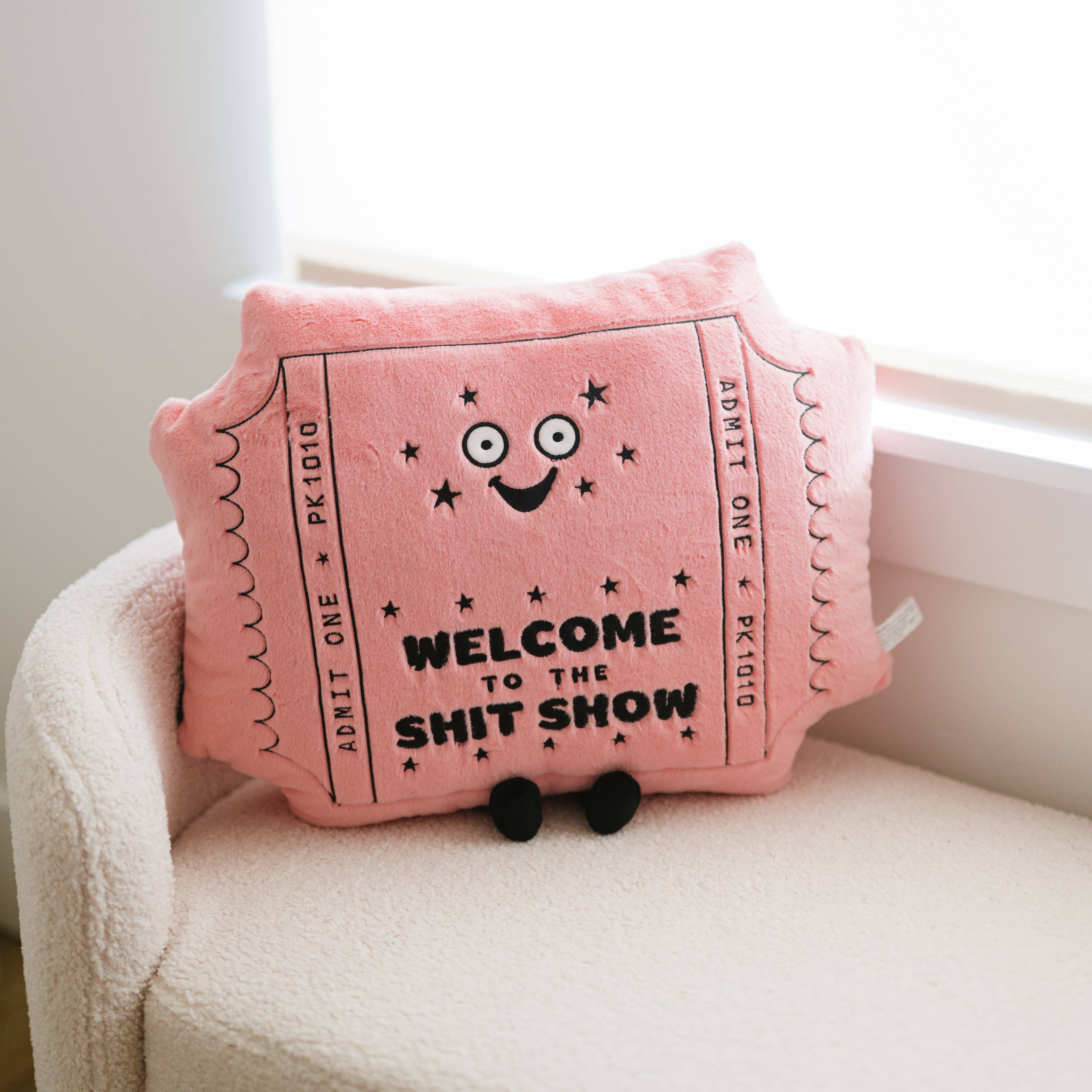 Cute pink pillow person shaped like a ticket that reads "welcome to the shit show" admit one.