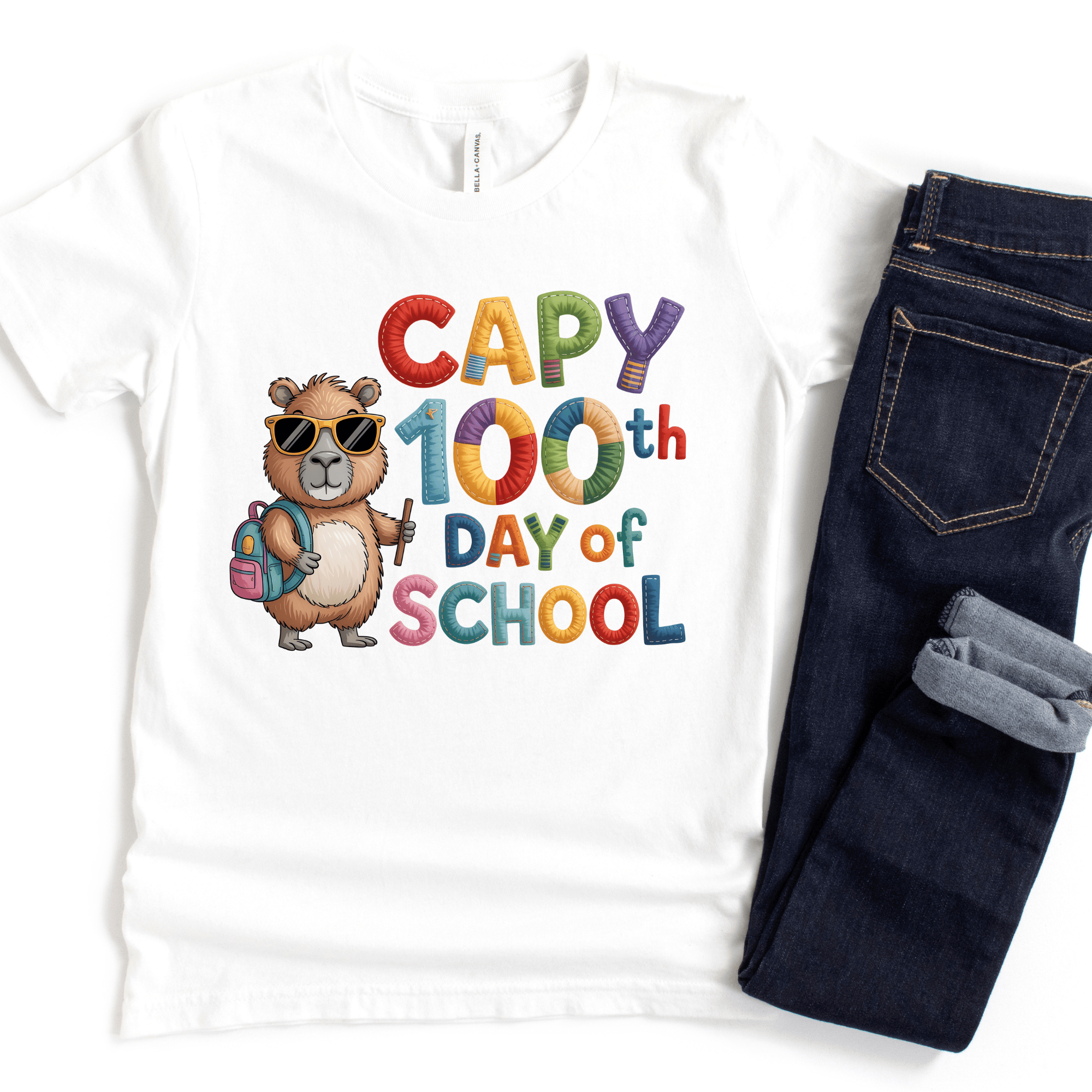 White t-shirt with a bear graphic and 'Capy 100th Day of School' text, paired with dark jeans.