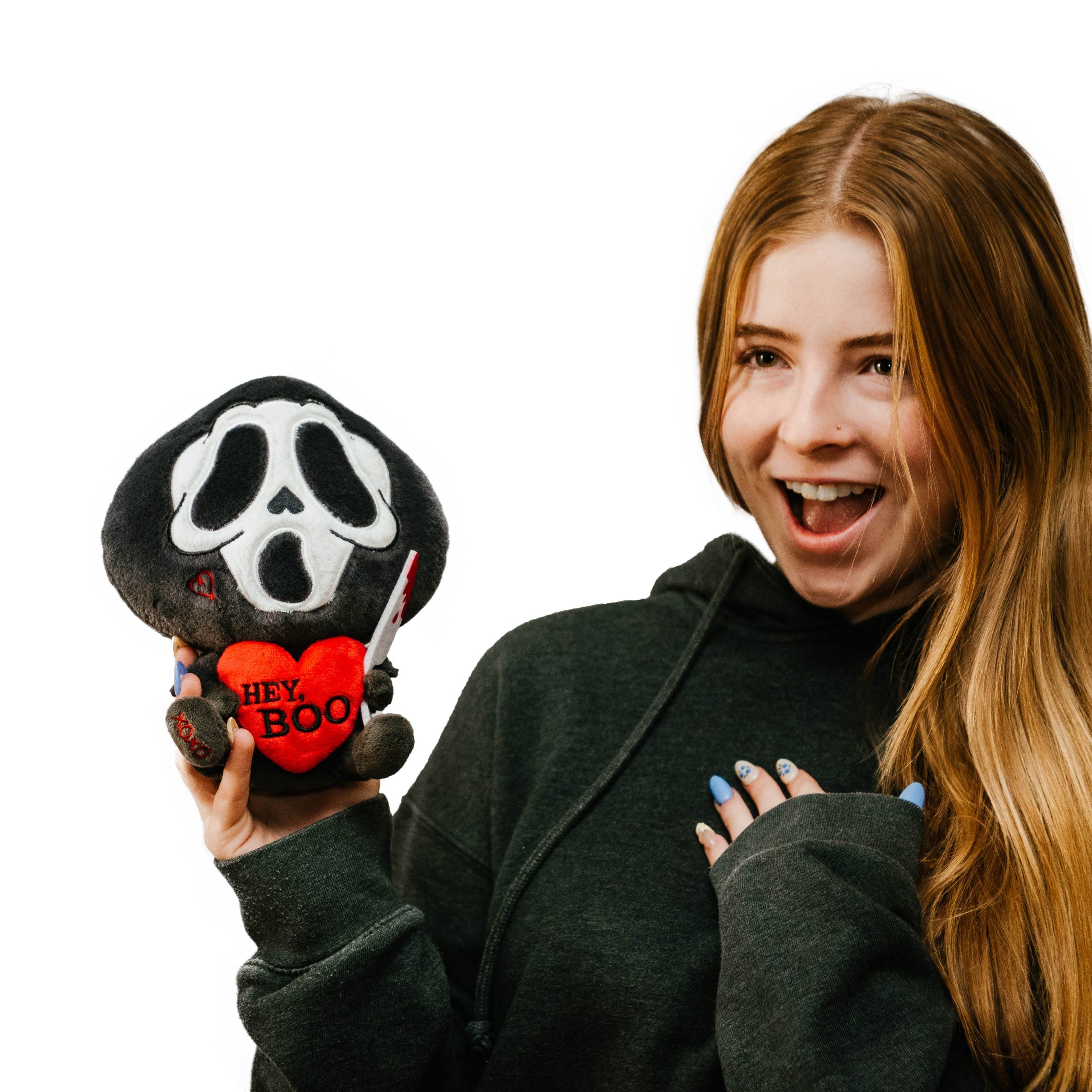 A black and white ghost resembling the Scream mask, holding a bloody knife in one hand and a red heart in the other. The heart has the phrase "Hey, Boo" written in black text.