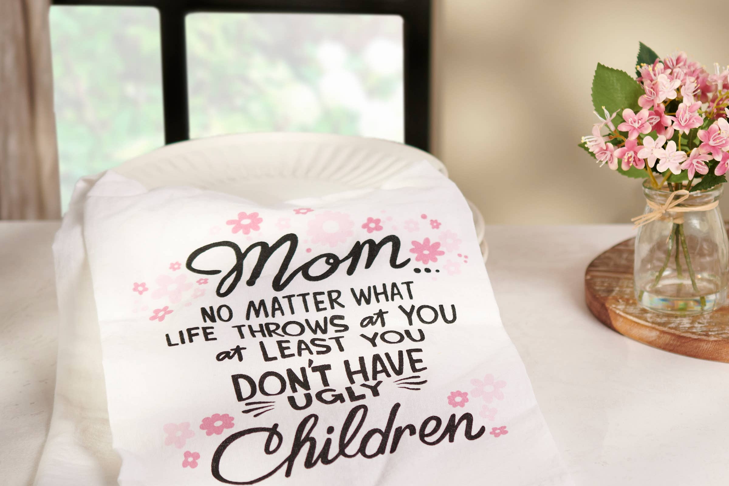 Blanket with humorous text on a table with a vase of flowers in the background