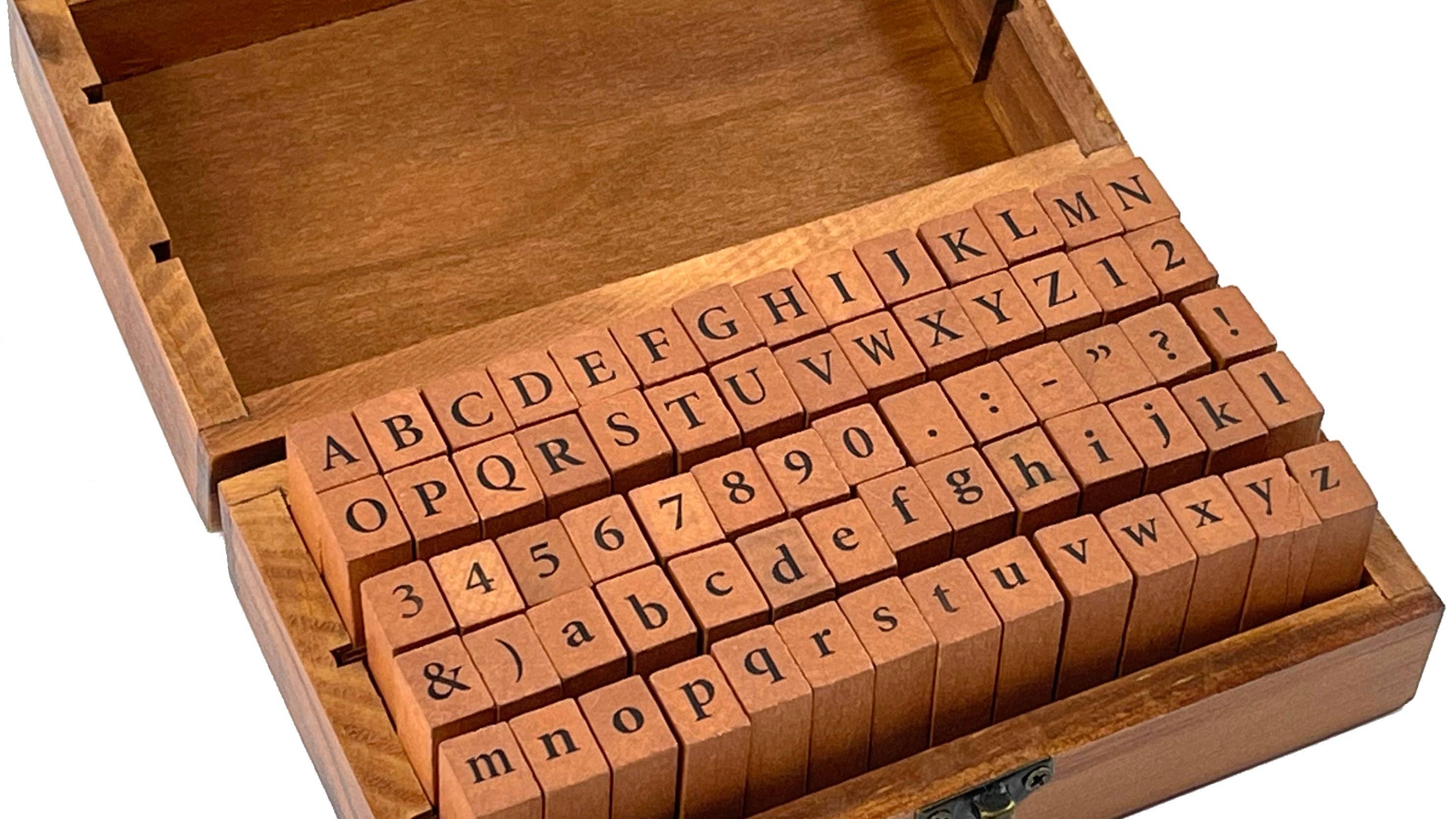 A wooden box with an open lid displays alphabet and number rubber stamps. The orderly arrangement conveys a sense of organization and creativity.