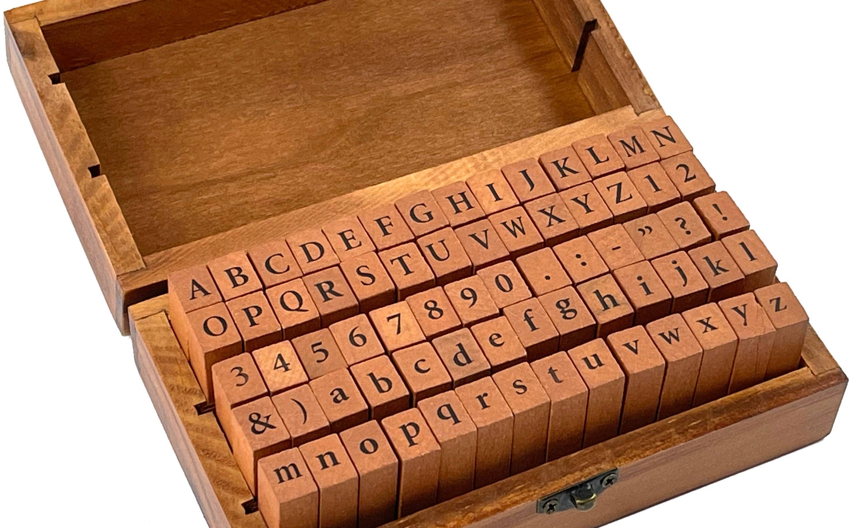 A wooden box with an open lid displays alphabet and number rubber stamps. The orderly arrangement conveys a sense of organization and creativity.