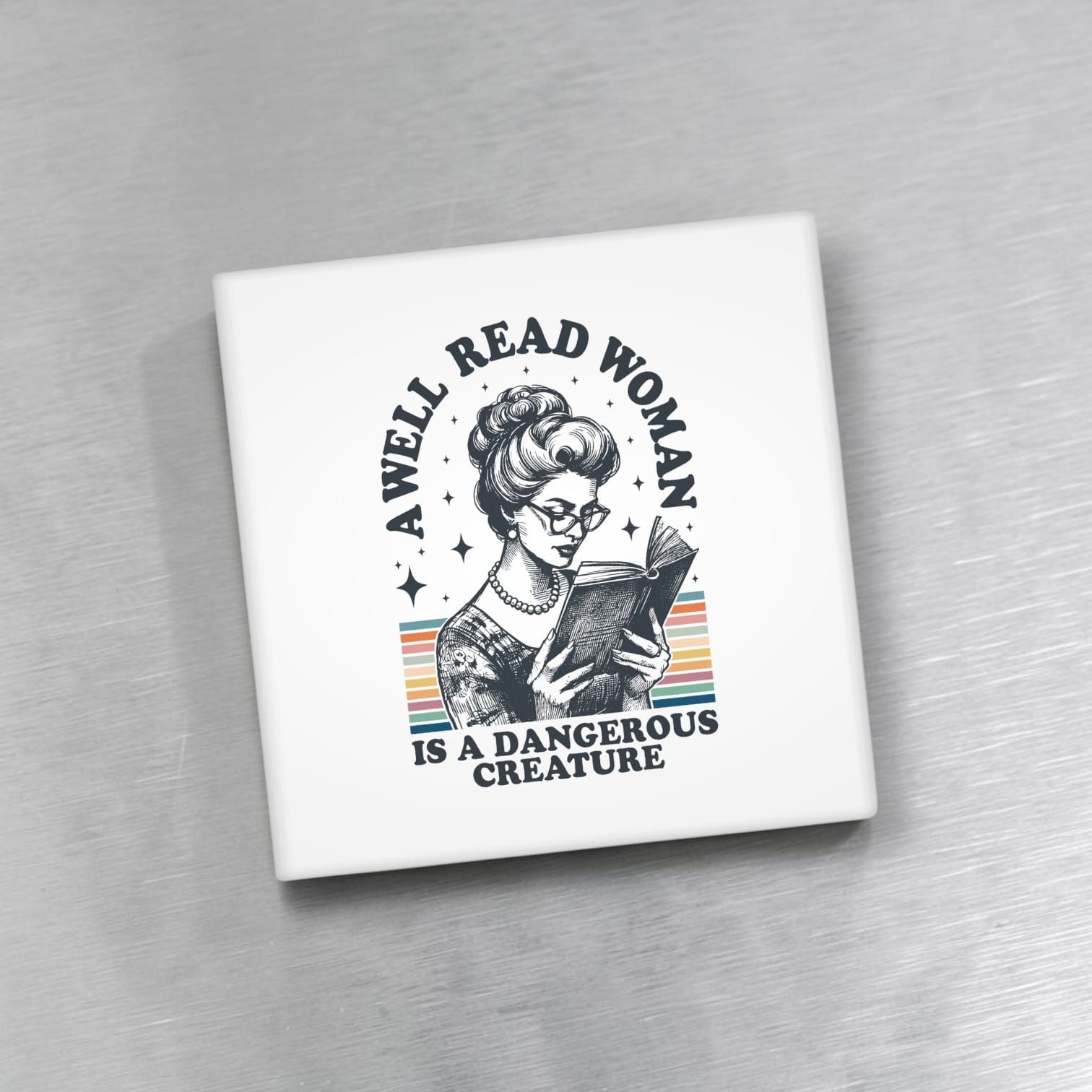 Square magnet with a graphic of a woman reading a book and text 'A well-read woman is a dangerous creature' on a gray background.