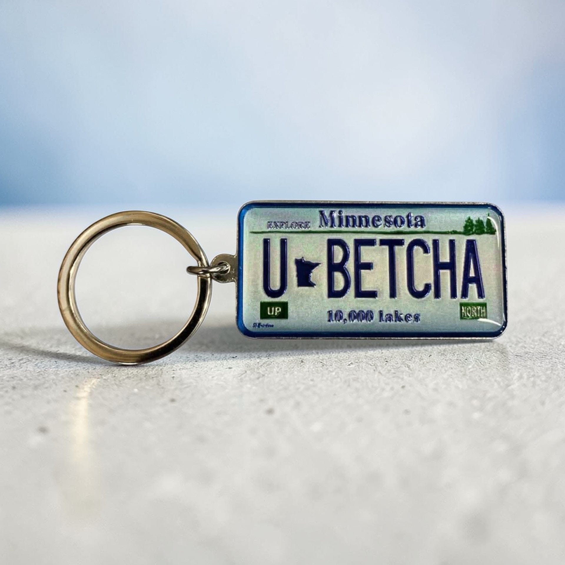 Keychain with Minnesota license plate design reading 'U-BETCHA' on a light background