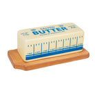 A butter-shaped stick resting on a wooden tray, labeled with blue text and measurements in tablespoons, mimicking packaging design, evokes humor.
