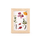 A wooden frame displaying pressed flowers and leaves arranged around two illustrated red fish with bubbles on a white background.