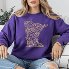 Person wearing a purple sweatshirt with yellow graphic design
