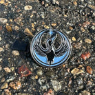 Rebel loon image as an enamel pin laying on a gravel background.