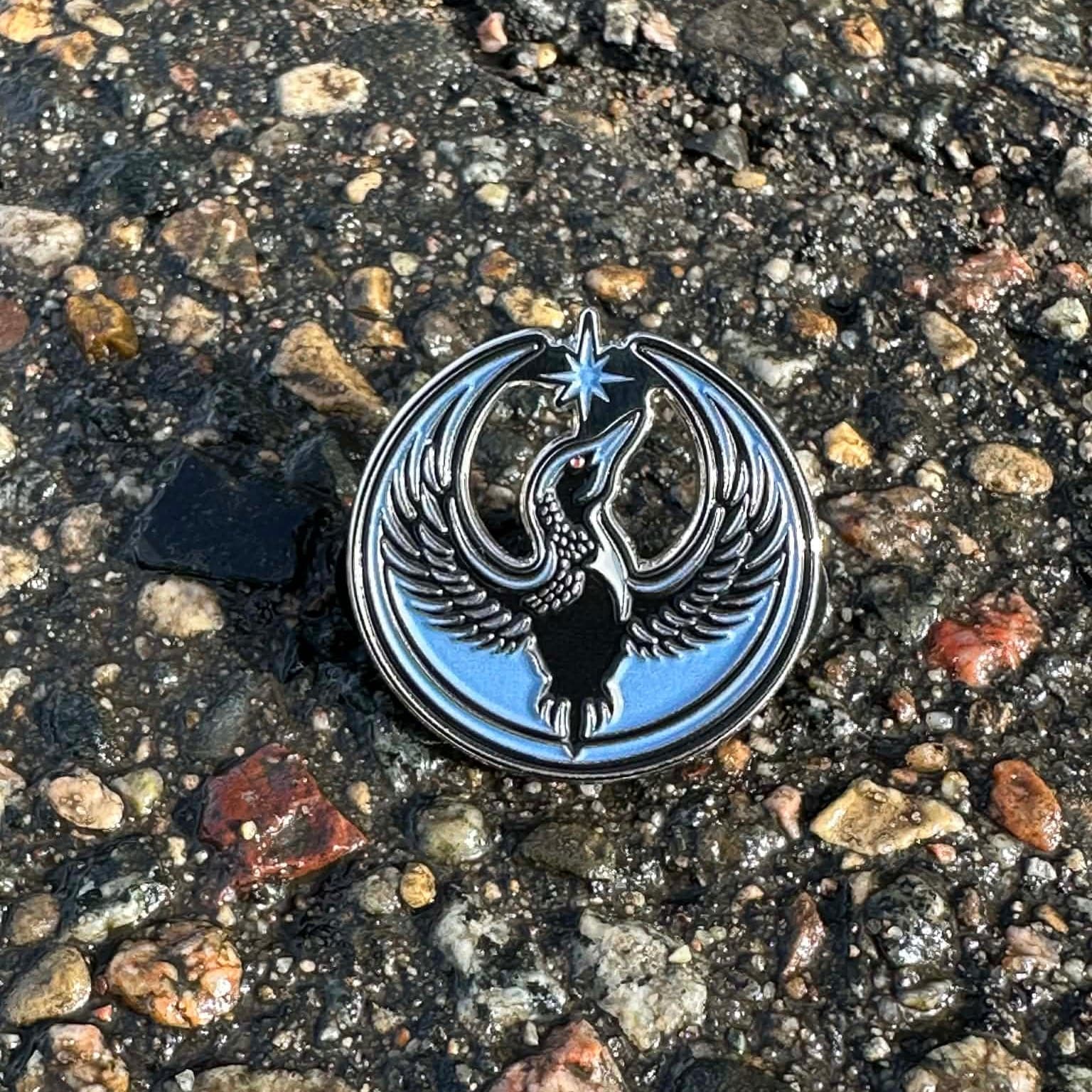 Metallic bird emblem on a textured asphalt surface