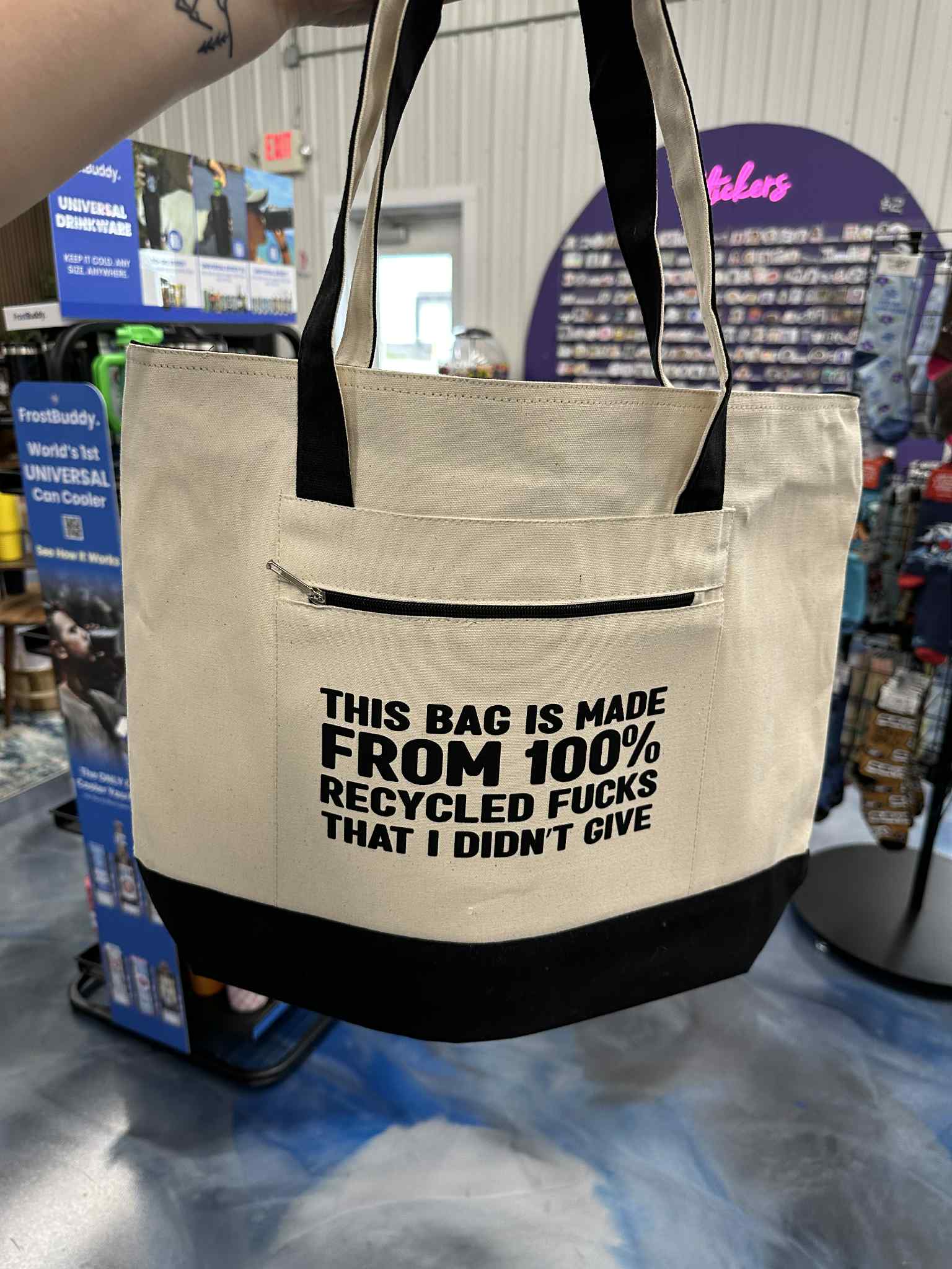 Beige tote bag with black text in a store setting