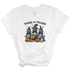 A white short-sleeve crewneck t-shirt with a graphic of three raccoons dressed as witches holding pumpkins, with the text 'TRICK OR TRASH' above them.