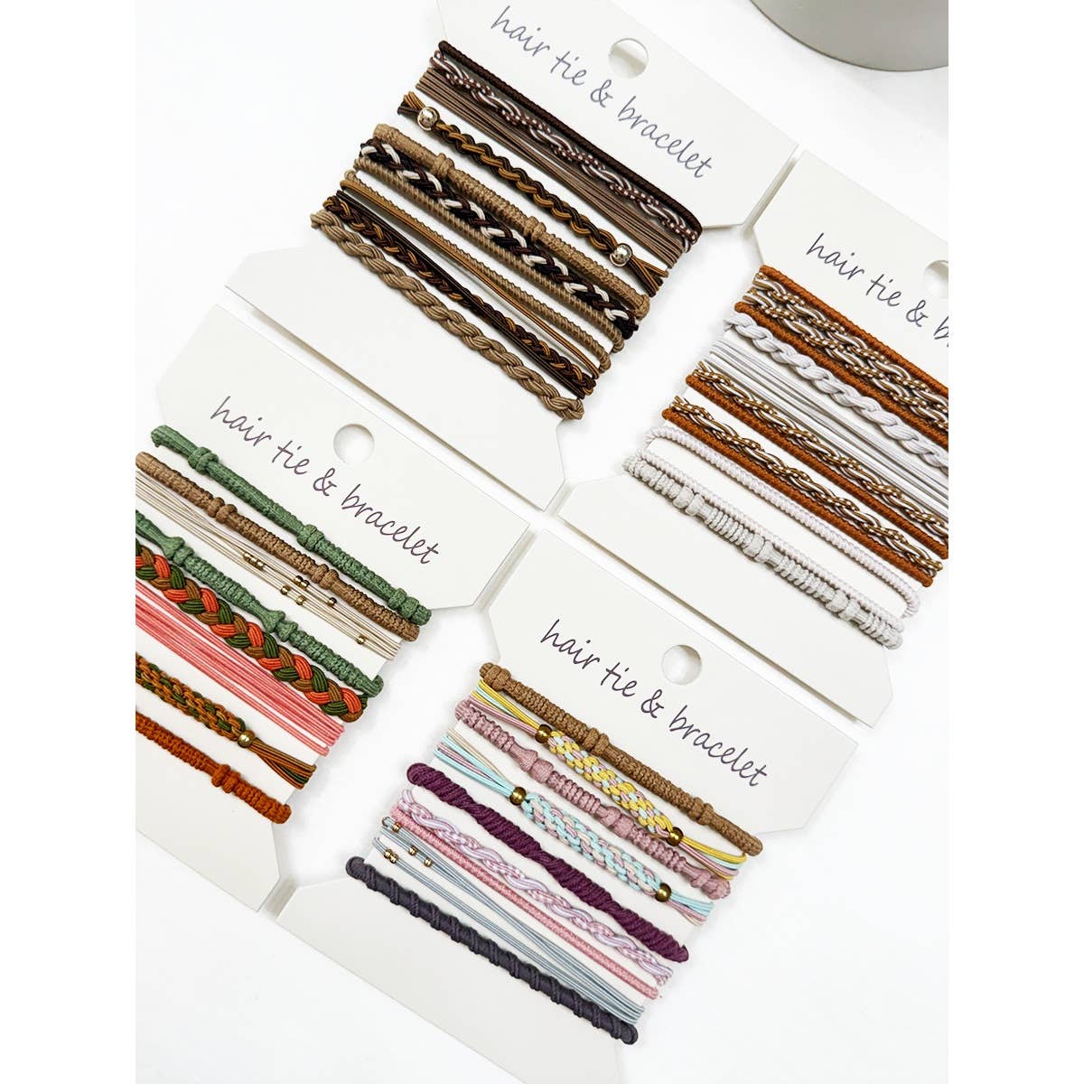 Assorted colorful hair ties and bracelets displayed on four white cards labeled "hair tie & bracelet," showcasing varying textures and patterns.