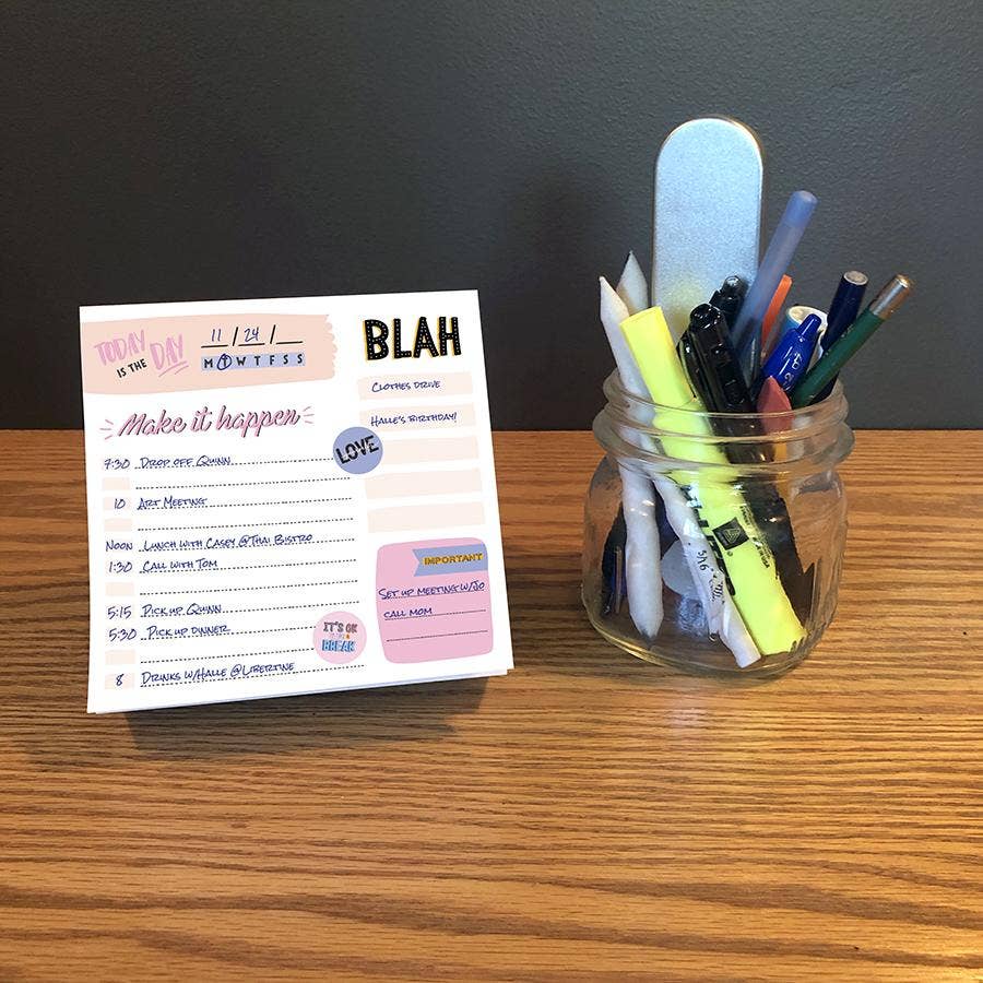 A desk displays a daily planner with a to-do list, titled "Make it happen," alongside a jar filled with markers, pens, and a nail file, conveying organization.