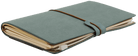 A closed gray-blue leather journal with a brown elastic strap, filled with slightly worn pages, rests on a transparent background. It conveys a vintage, well-used feel.