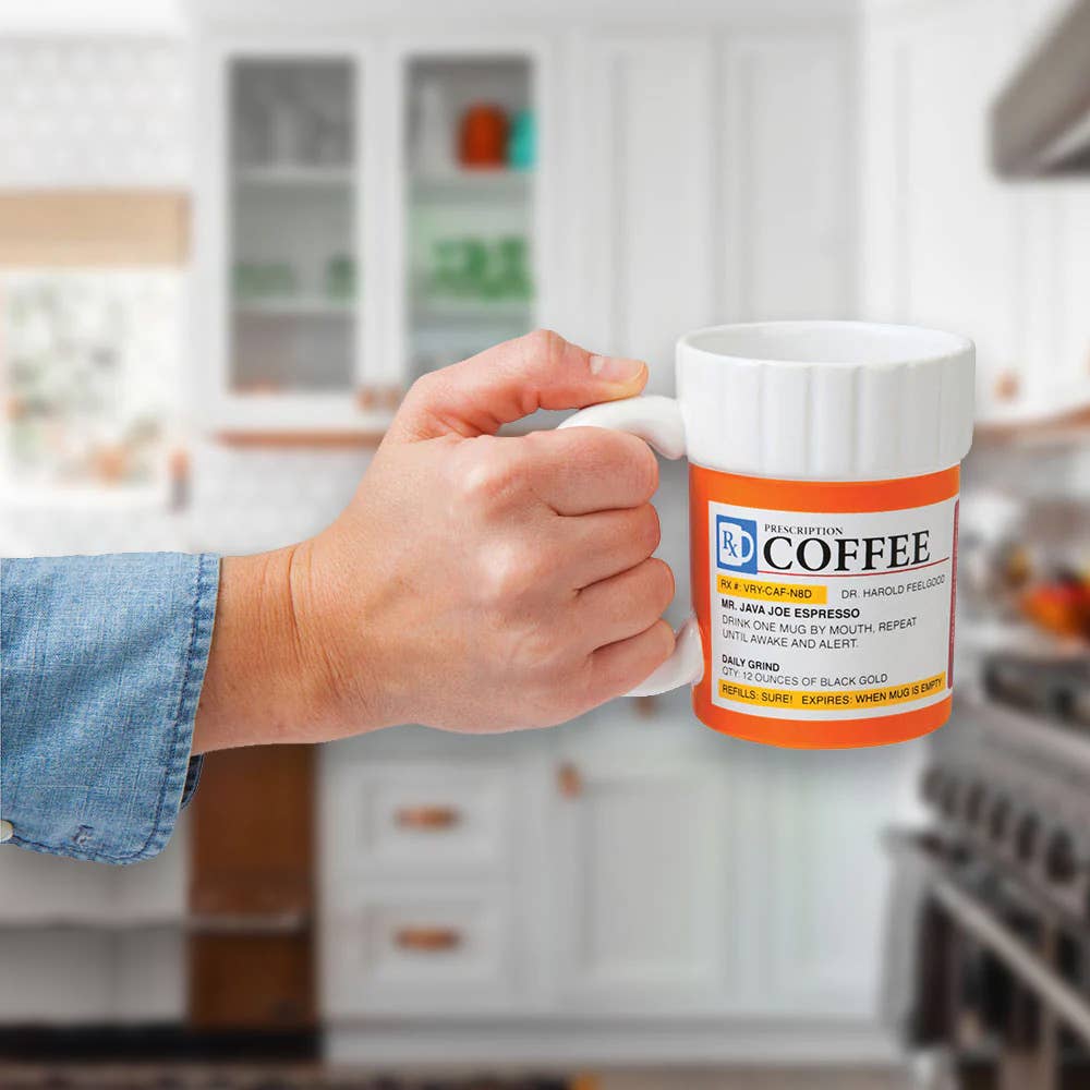A hand holds a coffee mug mimicking a prescription bottle, labeled "Prescription Coffee." The setting is a bright, blurred kitchen. Playful and humorous tone.