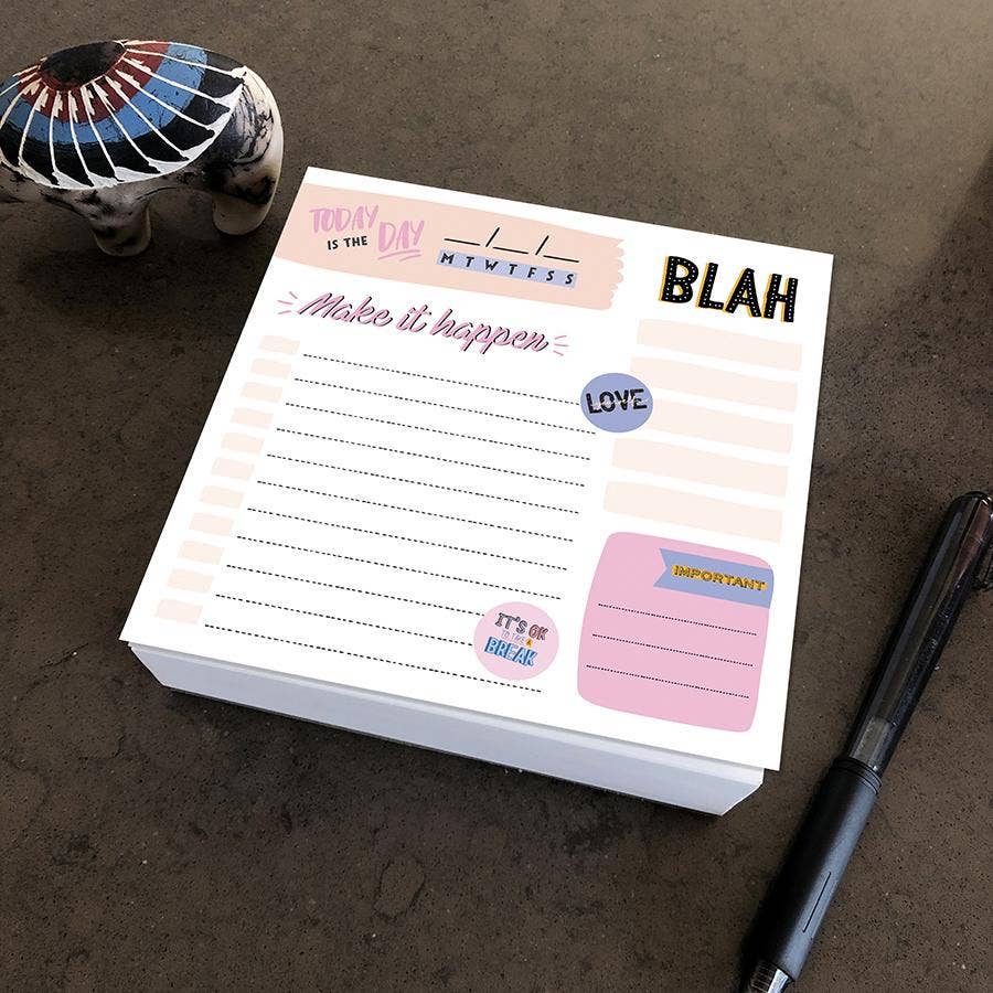 A colorful notepad on a table with sections labeled "Today is the day," and "Make it happen." Nearby is a pen and decorative elephant figurine.