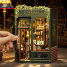 Miniature model of an owl bookstore with intricate details and a hand opening it.
