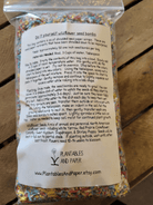 Clear plastic bag with multicolored shredded paper labeled “Do it yourself wildflower seed bombs.” Includes instructions and wildflower seed mix details.