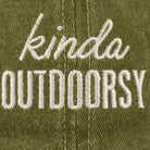 Close-up of green fabric with white embroidered text reading "kinda outdoorsy." The playful font and earthy tone suggest a casual, nature-themed vibe.