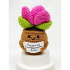 Crocheted succulent plant keychain with a brown pot and pink leaves on a white background, holding a sign that reads "thank you for helping me grow"
