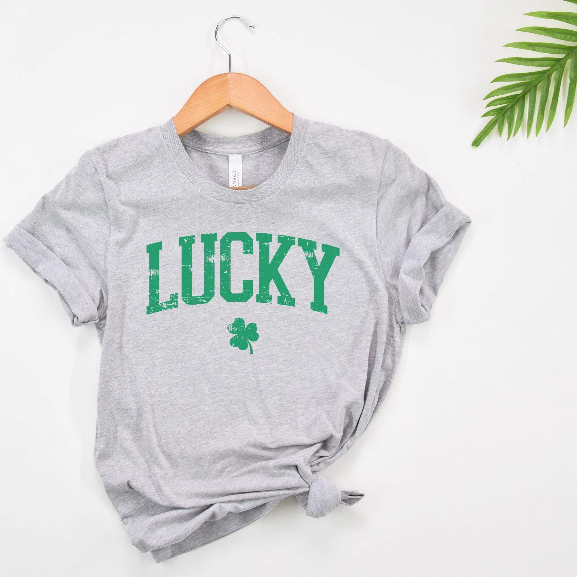 A gray t-shirt with the word 'LUCKY' printed in green letters, along with a small shamrock, also in green.